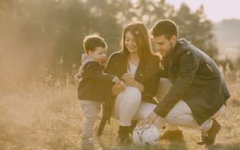 A cheerful family bonding outdoors with a soccer ball, enjoying a sunny day in the grass.